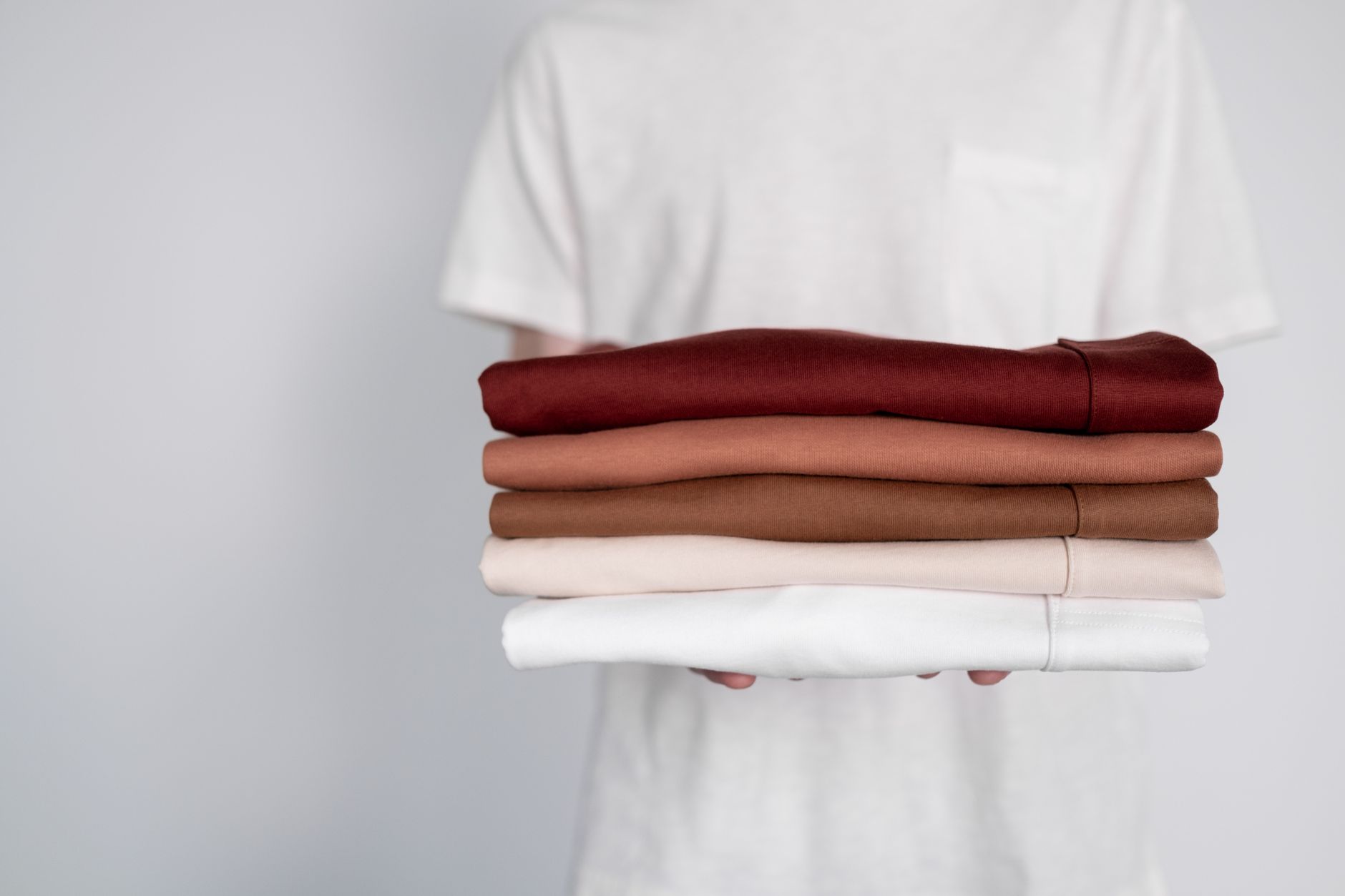 Neatly folded baby shirts in earthy tones