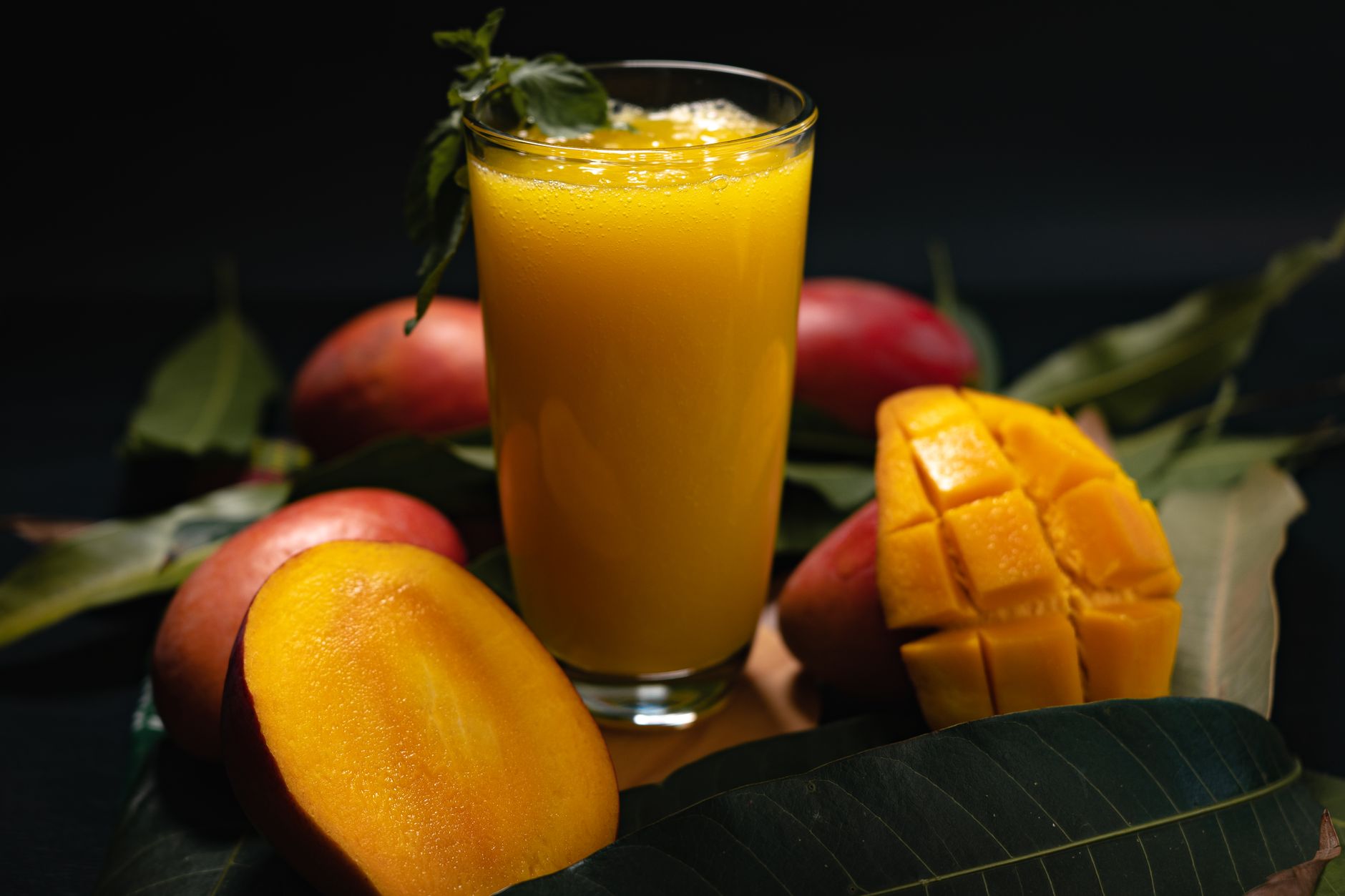 Delicious mango juice with sliced fruit on dark background, highlighting freshness and nutrition.