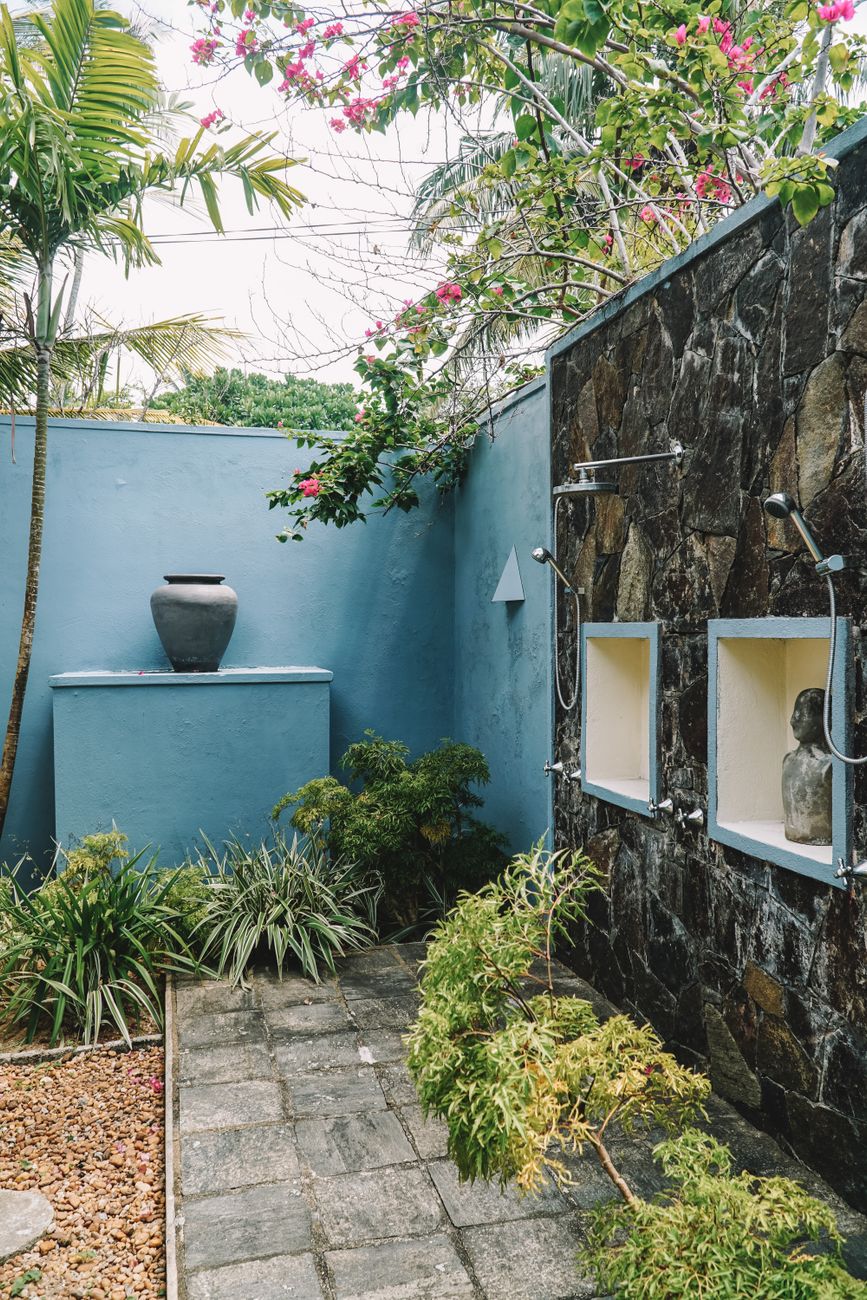 Serene outdoor shower space with vibrant flora in a Sri Lankan garden.